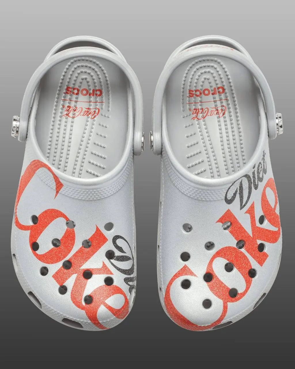 Coca Cola в коллабе с Crocs дропнула две пары клоггов — с отсылкой на классическую красную колу (с джиббитсами мишкой и крышечкой от газировки) и с отсылкой на диетическую серебристую колу | Сетка — социальная сеть от hh.ru